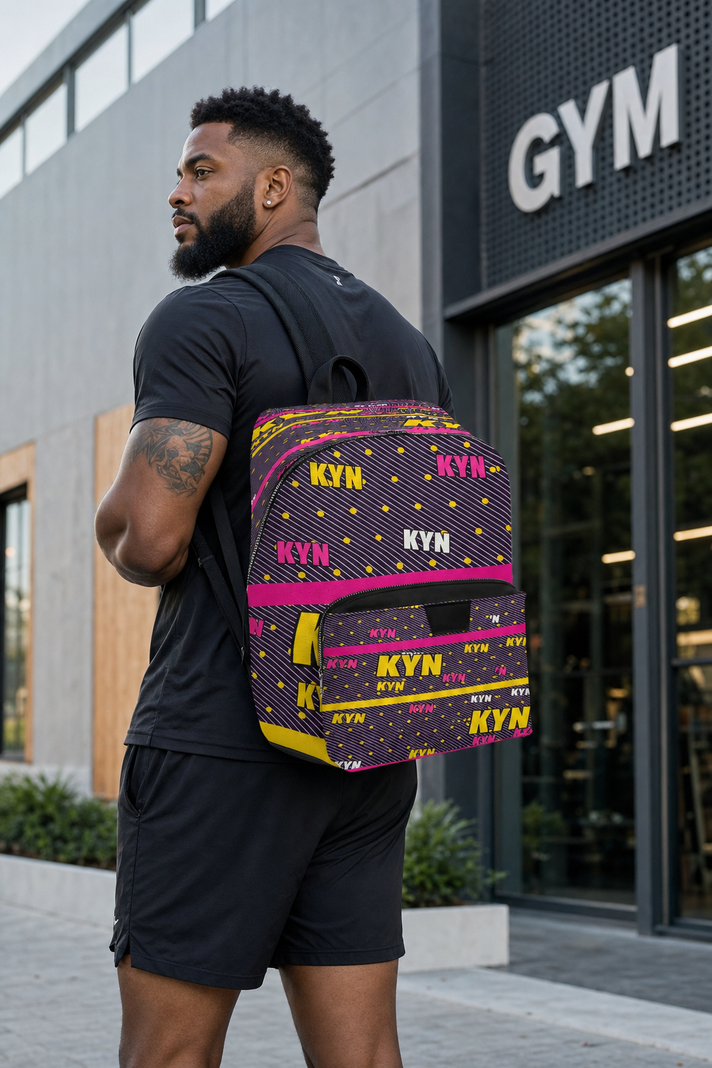 Man with a colorful backpack standing in front of a gym entrance