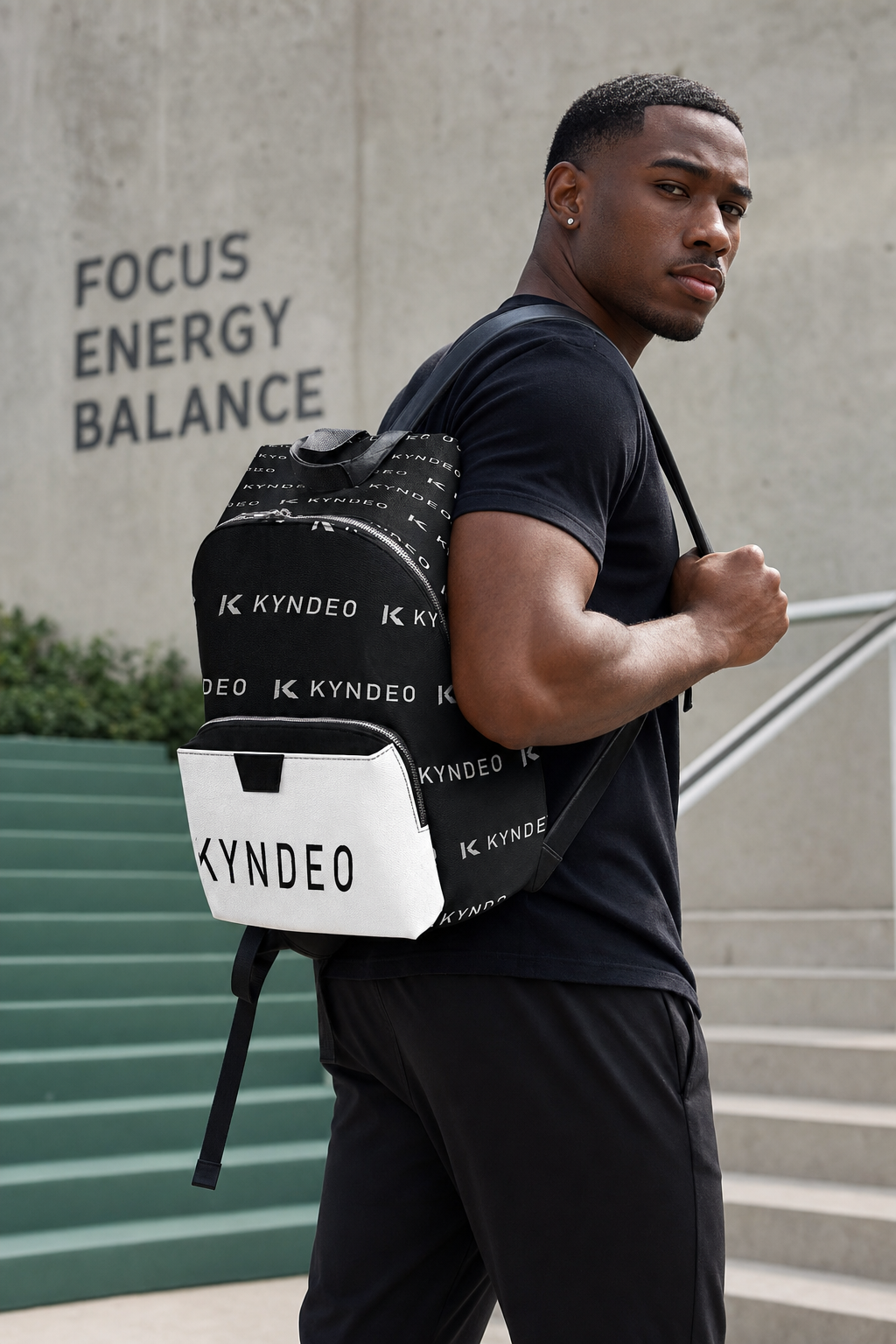 Man wearing a black backpack with 'KYNDEO' branding against a concrete wall with motivational text.