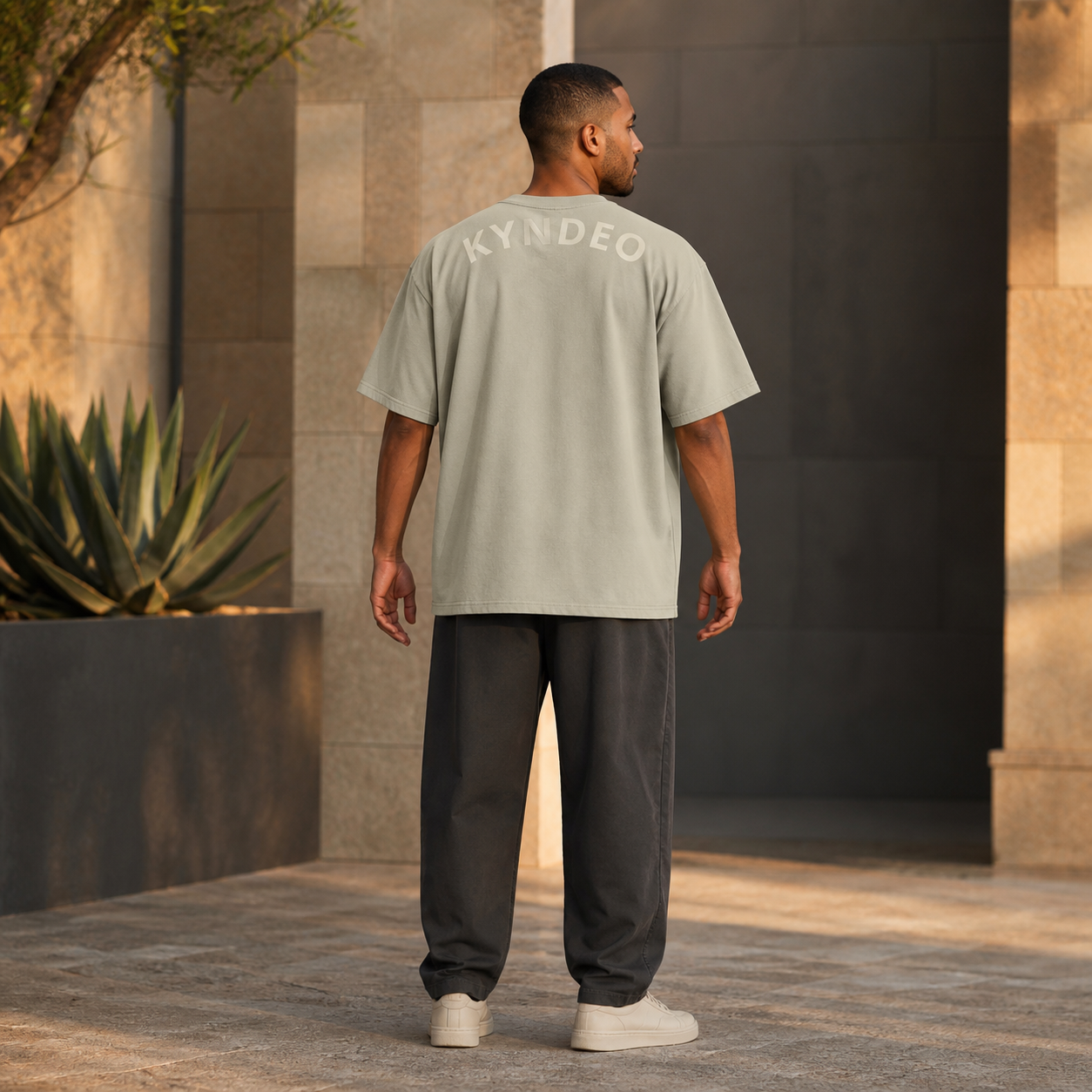 KYNDEO Fadeweight Oversized Tee in faded eucalyptus, complete rear three-quarter lifestyle view on an Afro-Latino male model showing the rear KYNDEO wordmark
