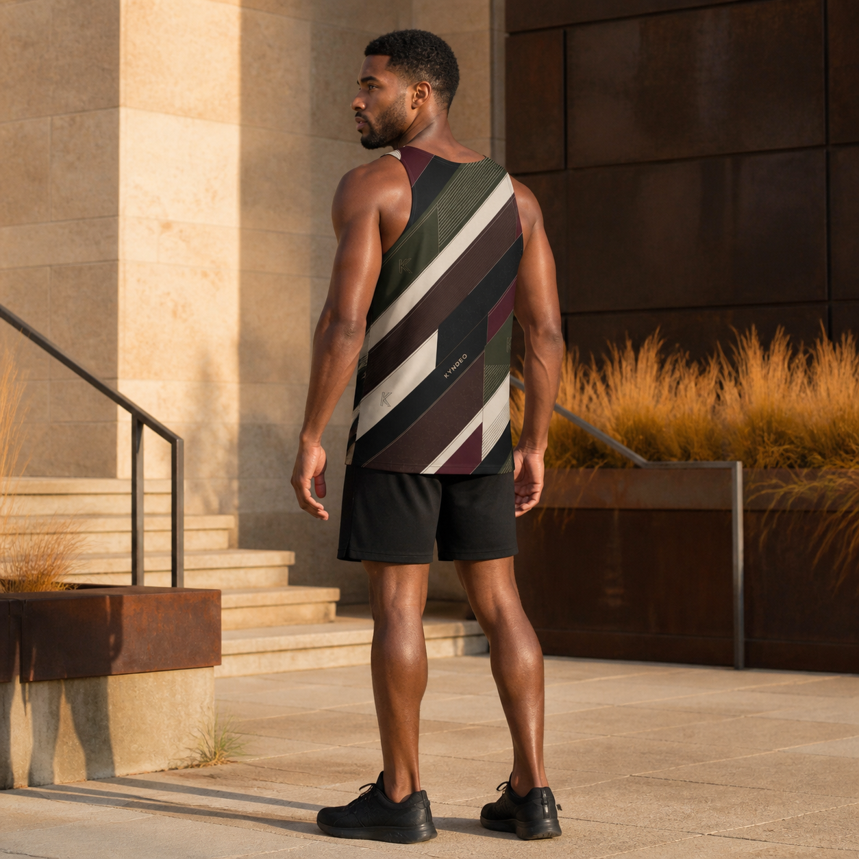KYNDEO Apex Tank complete rear three-quarter lifestyle view showing side-wrap continuity on an Afro-Latino male model