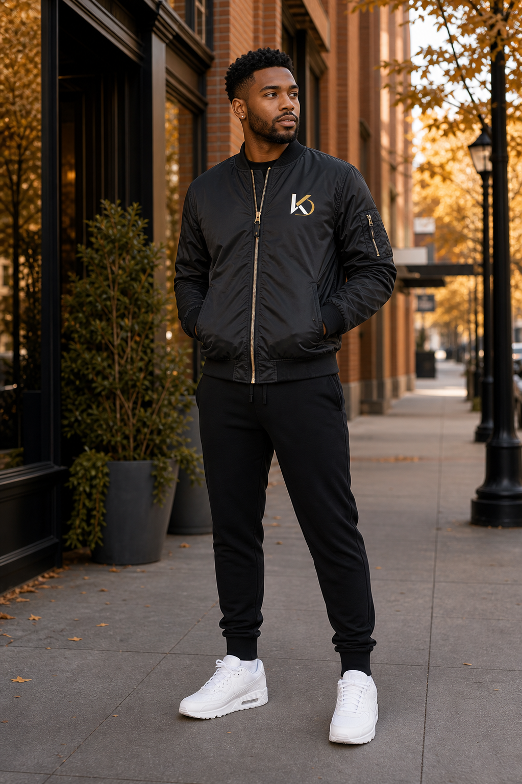 Black male model wearing the KYNDEO Flight Bomber Jacket on a fall sidewalk