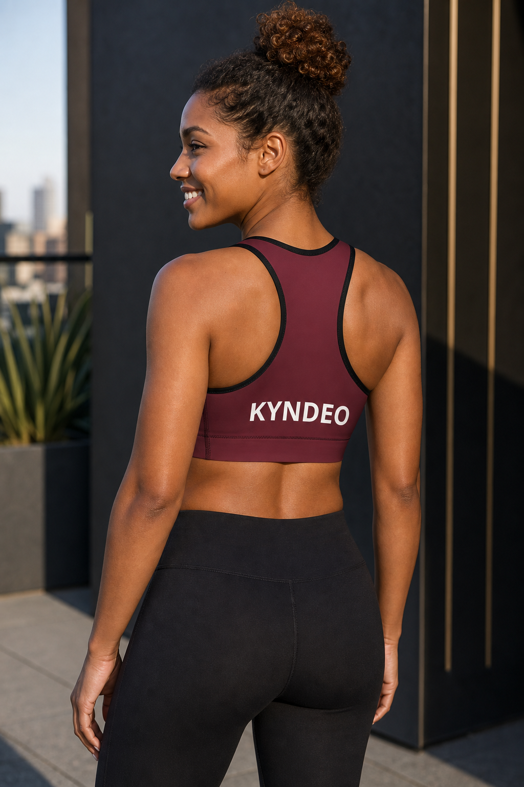 Afro-Latina woman wearing KYNDEO Oxblood Sports Bra, rear three-quarter view